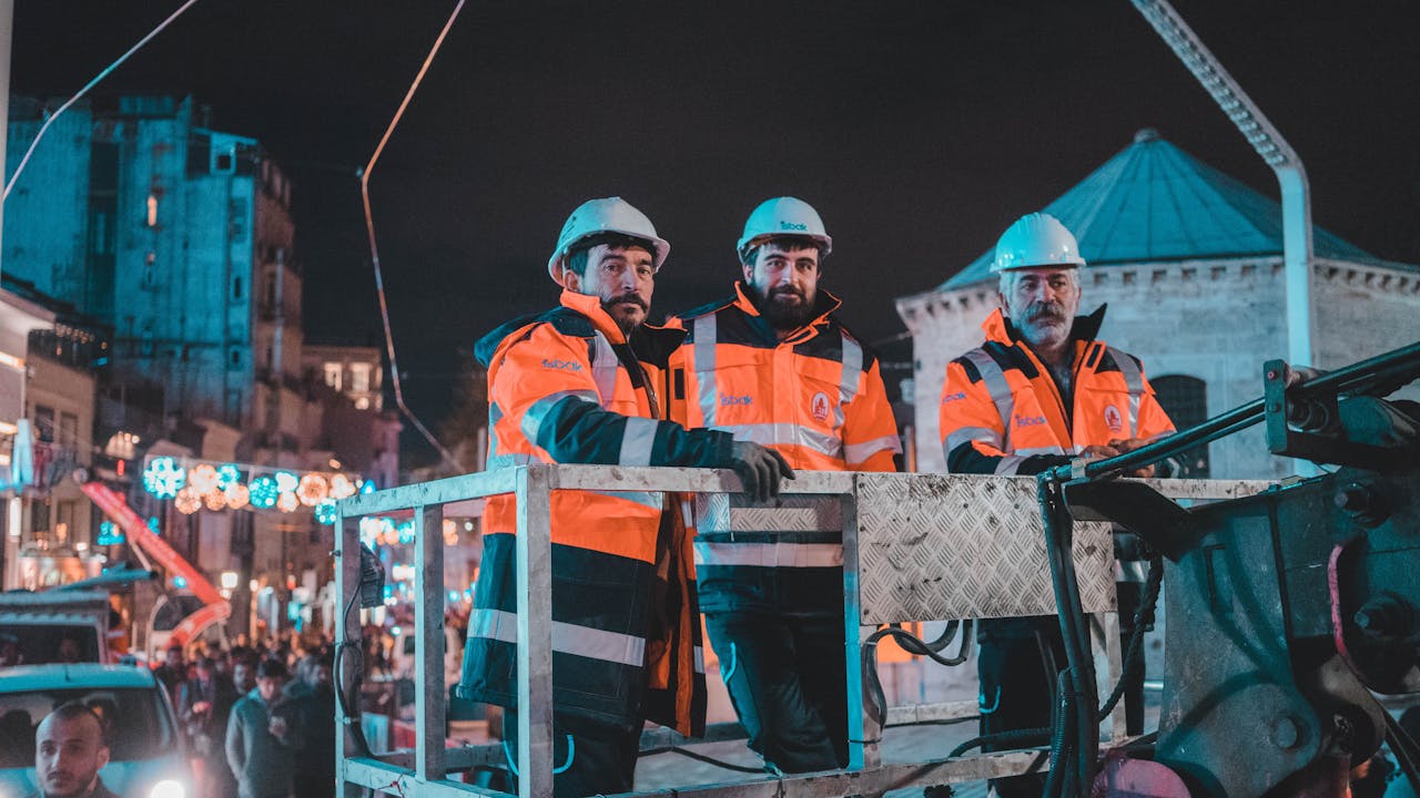 A group of construction workers in Istanbul wearing hardhats and jackets during nighttime work.
